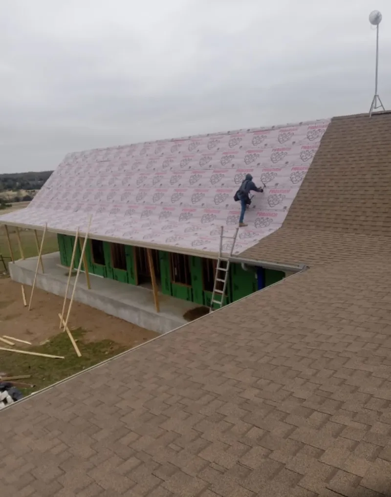 Worker preparing underlayment for a metal roof installation in Whitefish